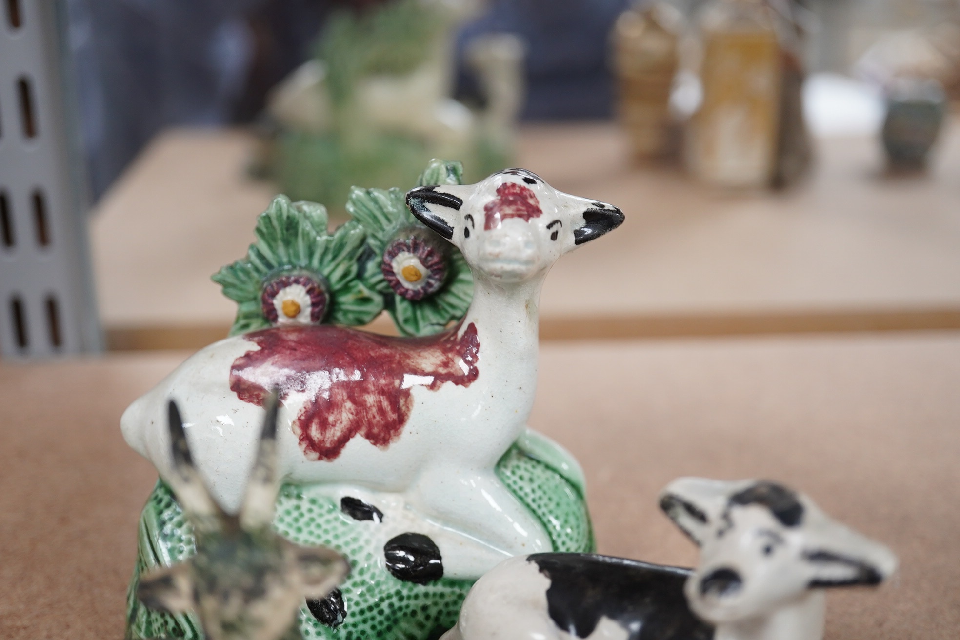 Two late 18th century Staffordshire coloured creamware figures of recumbent cows and a spongeware deer, largest 10cm wide (3). Condition - restored